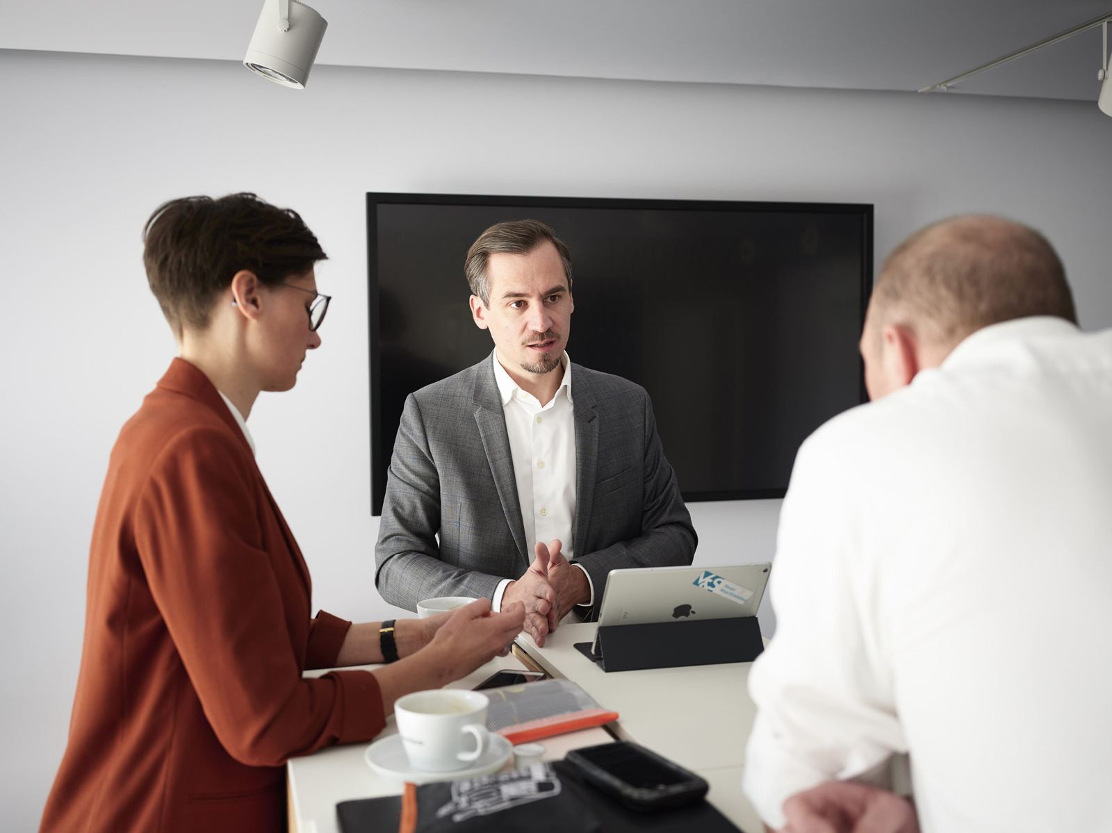 Drei Personen im Gespräch an einem Besprechungstisch mit Laptop
